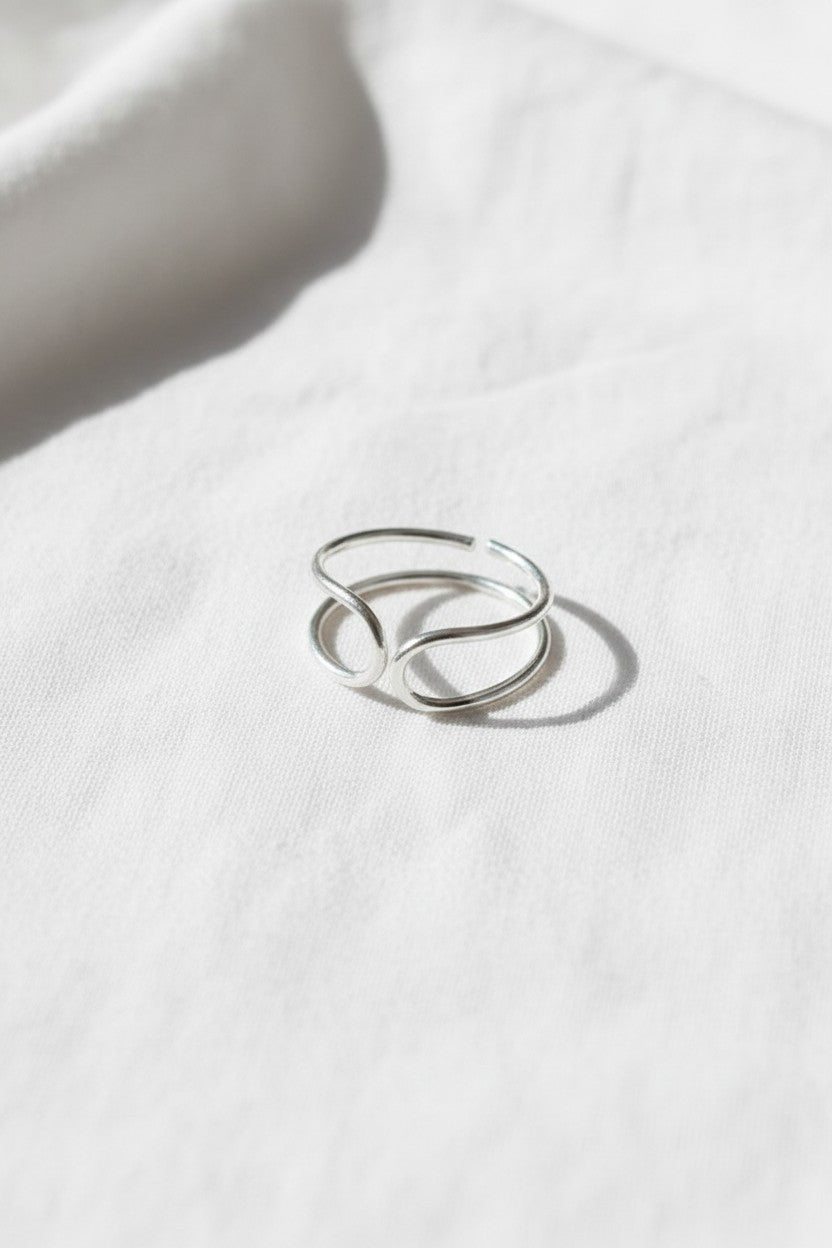 Anillo doble abierto de plata de ley 925 de Calendula-shop sobre fondo de tela blanca
