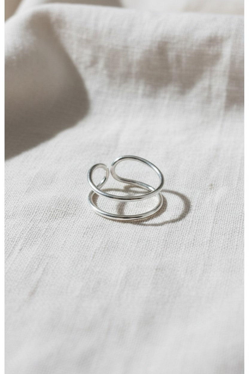 Anillo doble abierto de plata de ley 925 de Calendula-shop sobre fondo de tela clara