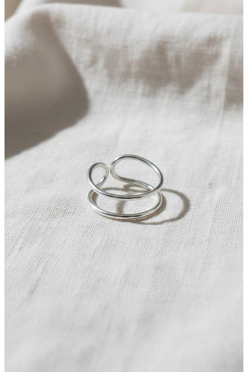Anillo doble abierto de plata de ley 925 de Calendula-shop sobre fondo de tela clara