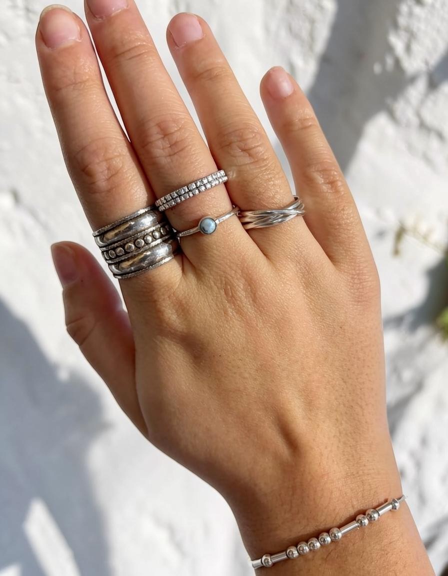 Anillo fino de plata de ley 925 con piedra natural de Larimar de Calendula-shop, lucido en la mano junto a otros anillos