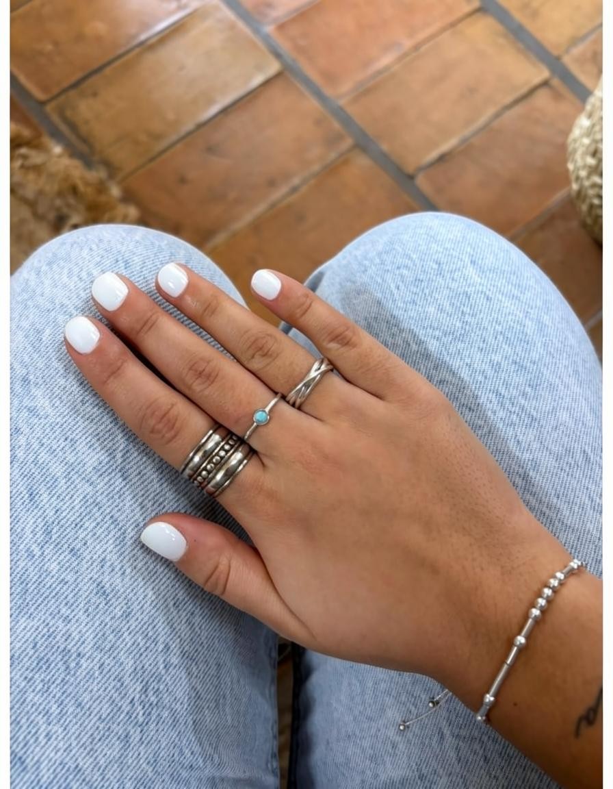 Anillo fino de plata de ley 925 con piedra natural de Larimar de Calendula-shop, lucido en mano con manicura blanca.