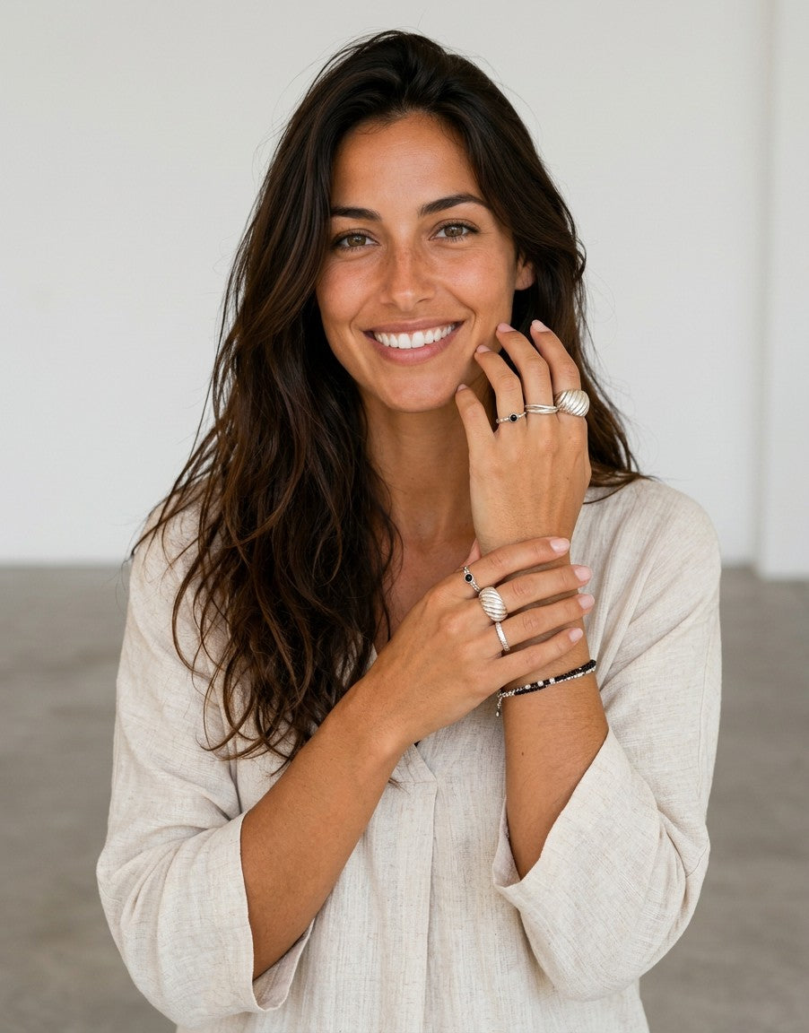 Modelo sonriente luciendo el anillo Ubud de plata de ley 925 de Calendula-shop con diseño ancho y hendiduras.