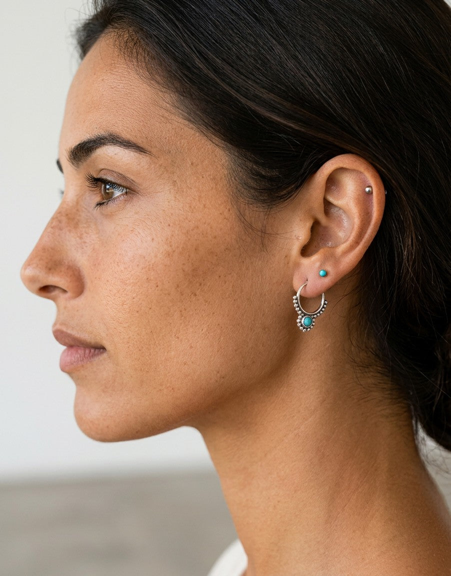 Aritos Beatrice de Calendula-shop en plata de ley 925 con piedra turquesa, puestos en la oreja de una modelo.