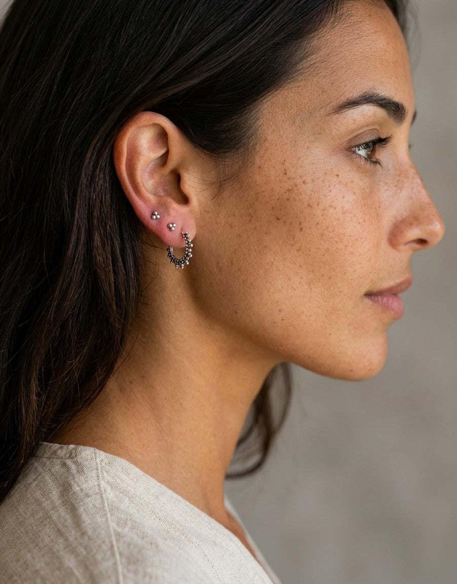 Aros étnicos Andry de Calendula-shop en plata de ley 925 con diseño labrado tipo sol, puestos en una modelo.