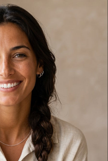 Mujer sonriente con aros básicos de plata de ley 925 de Calendula-shop, estilo minimalista y cierre congo.