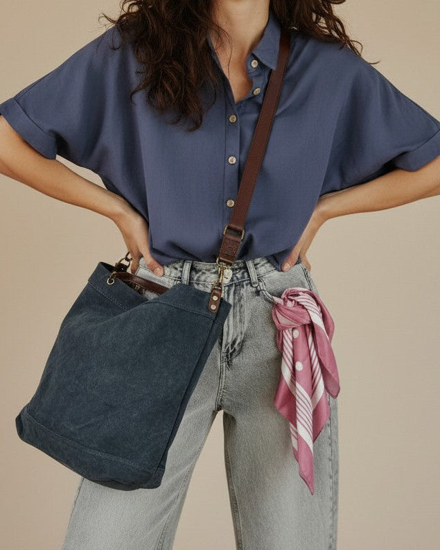 Calendula-shop blue canvas tote bag with brown leather straps worn by a smiling woman in a casual outfit