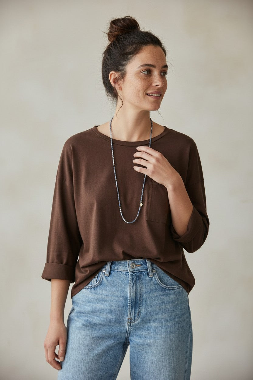 Calendula-shop brown long-sleeve cotton t-shirt with a chest pocket worn by a woman with a bun hairstyle