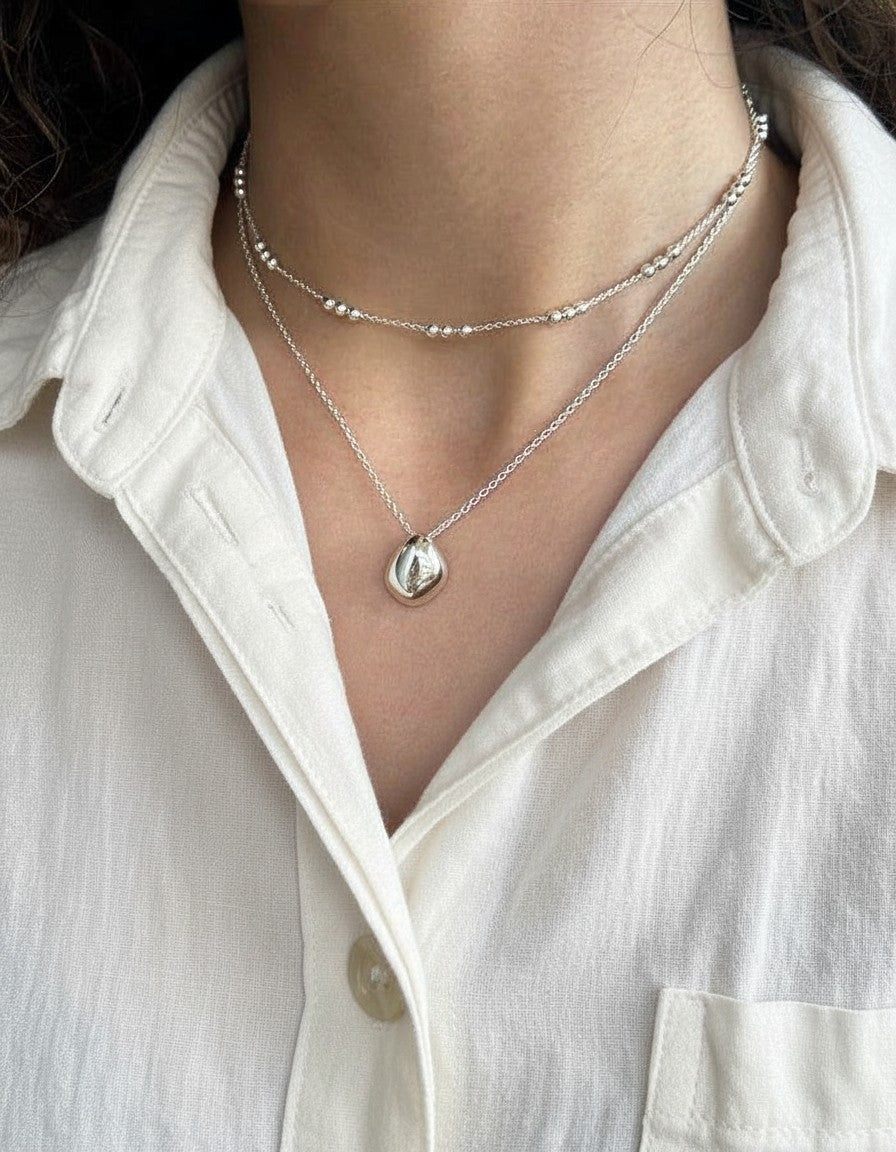 Cadena de bolitas Calendula-shop de plata de ley con diseño minimalista y elegante sobre camisa blanca