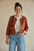 Modelo sonriente vistiendo la chaqueta corta Julia de Calendula-shop en color teja con detalles bordados en bolsillos