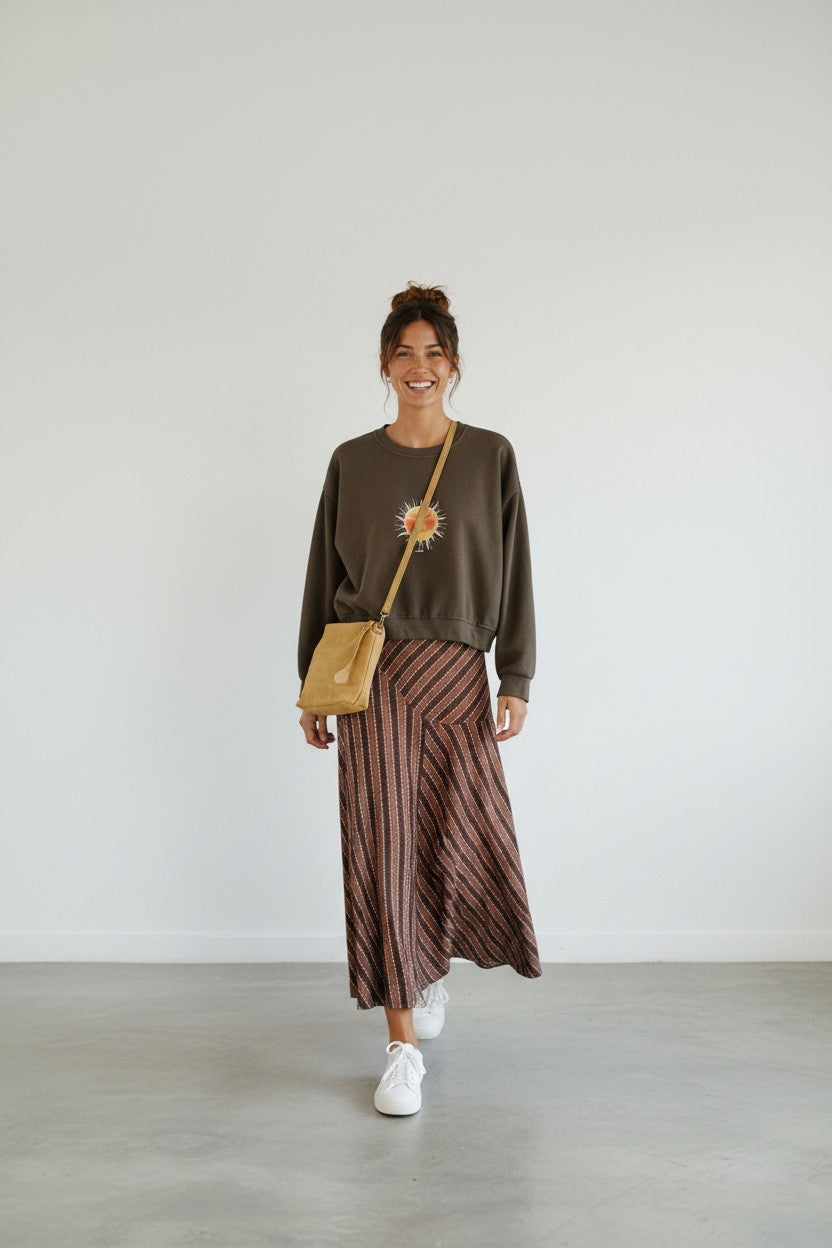 Calendula-shop chocolate brown cropped sweatshirt with exclusive sun graphic, worn with a striped midi skirt