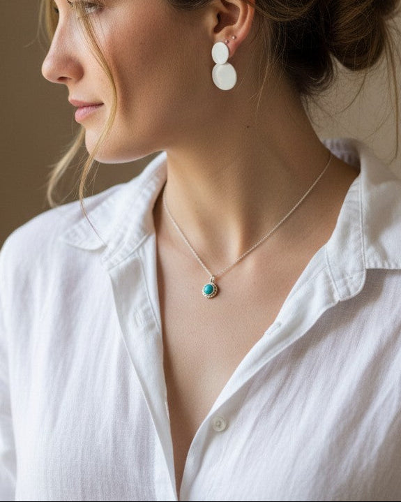 Colgante Cosmos de Calendula-shop en plata de ley con piedra ágata fucsia, lucido por una mujer con camisa blanca.