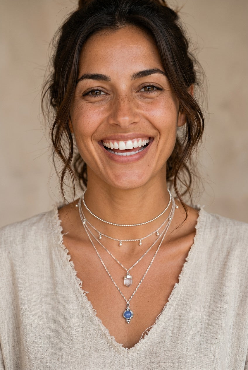 Mujer sonriente luciendo el colgante Eter de Calendula-shop con piedra de calcedonia azul y cadena de plata fina.