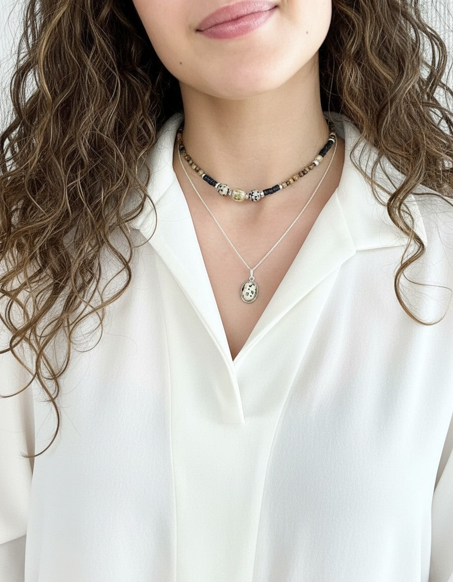 Colgante Calendula-shop de piedra dálmata ovalada con cadena de plata de ley sobre modelo con camisa blanca