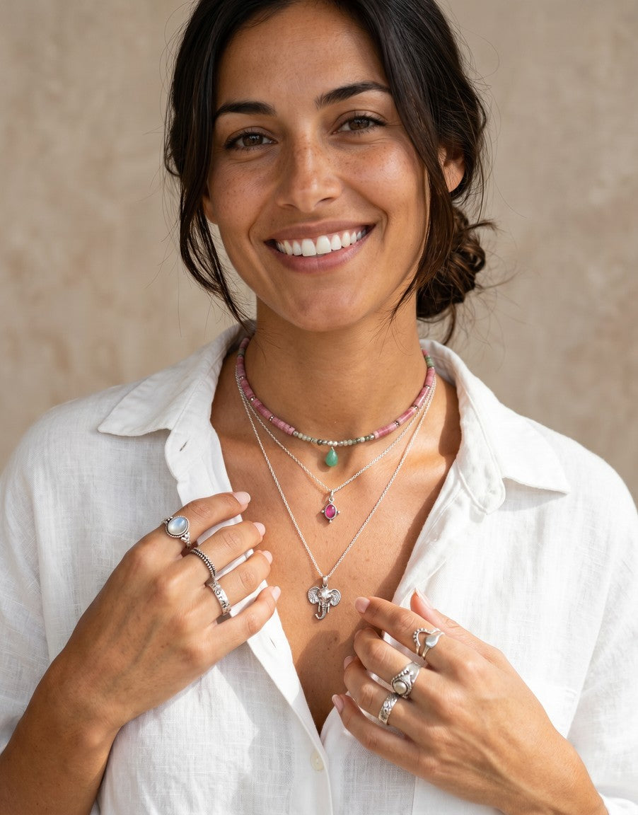 Mujer sonriente luciendo collares y anillos de plata con piedras naturales de Calendula-shop