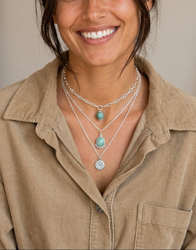 Mujer sonriente luciendo un colgante de plata de ley con piedra natural amazonita de Calendula-shop