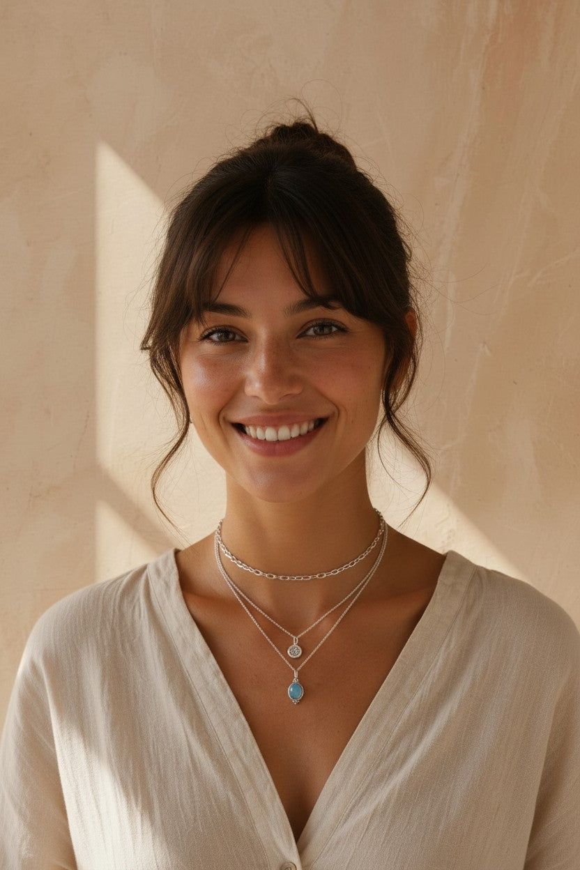 Mujer sonriente luciendo el colgante Fluye de Calendula-shop en plata de ley con piedra calcedonia celeste.