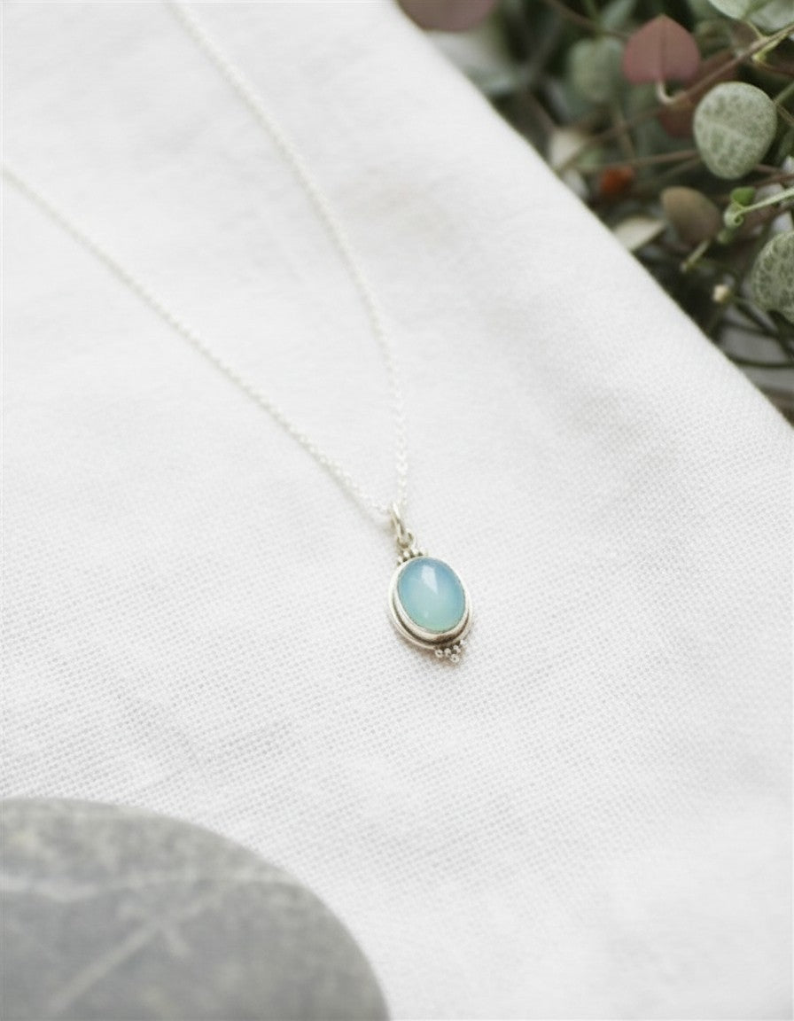Colgante Calendula-shop de plata de ley con piedra calcedonia celeste en forma ovalada sobre tela blanca