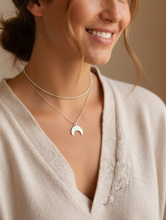 Mujer sonriente luciendo un colgante de plata de ley 925 con diseño de fases lunares de Calendula-shop