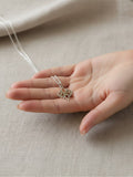 Colgante LONDON de Calendula-shop en plata de ley 925 con diseño de hojas ovaladas sobre mano femenina.