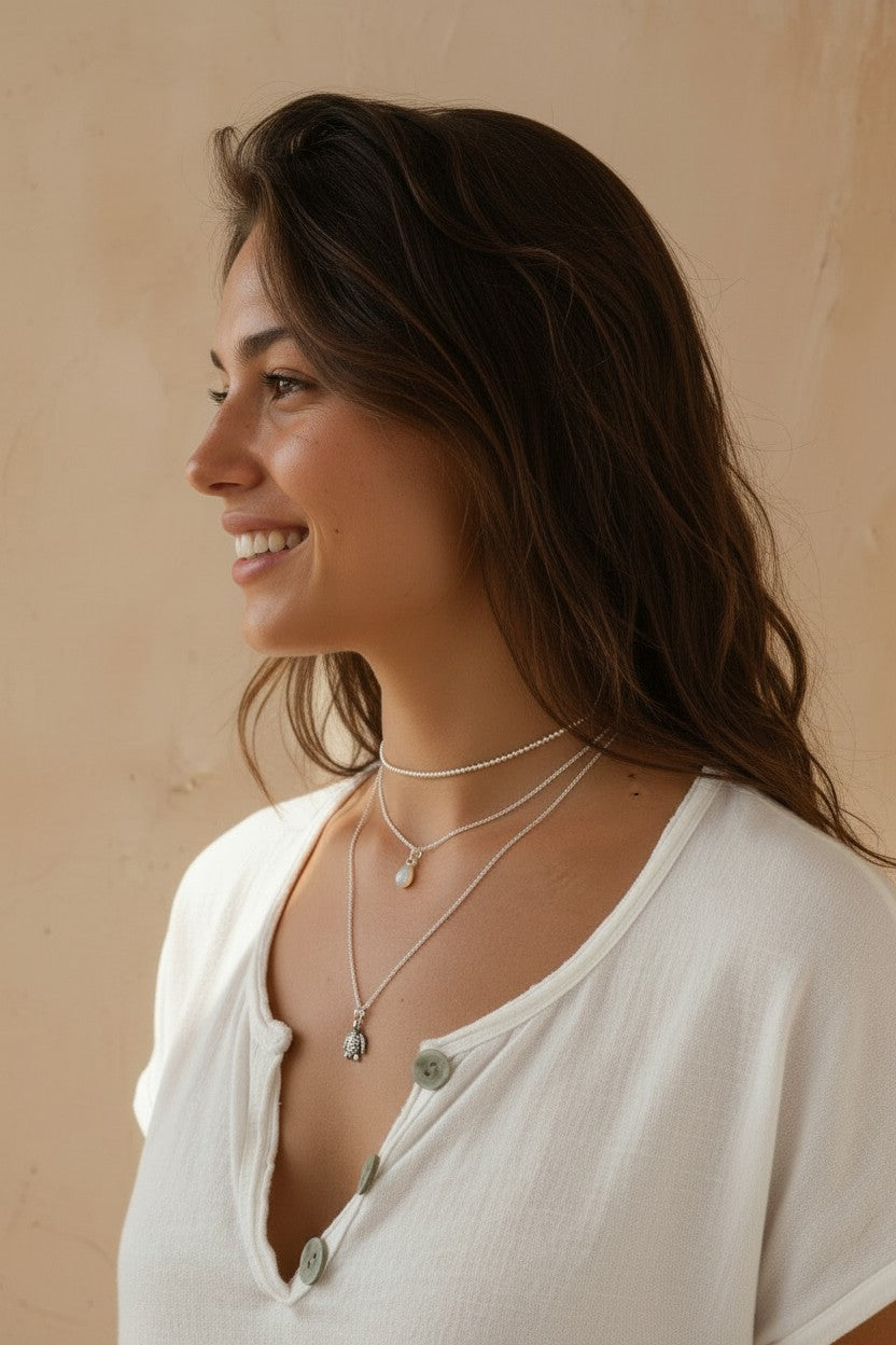 Mujer sonriente luciendo un colgante de tortuga de plata de ley de Calendula-shop con cadena fina