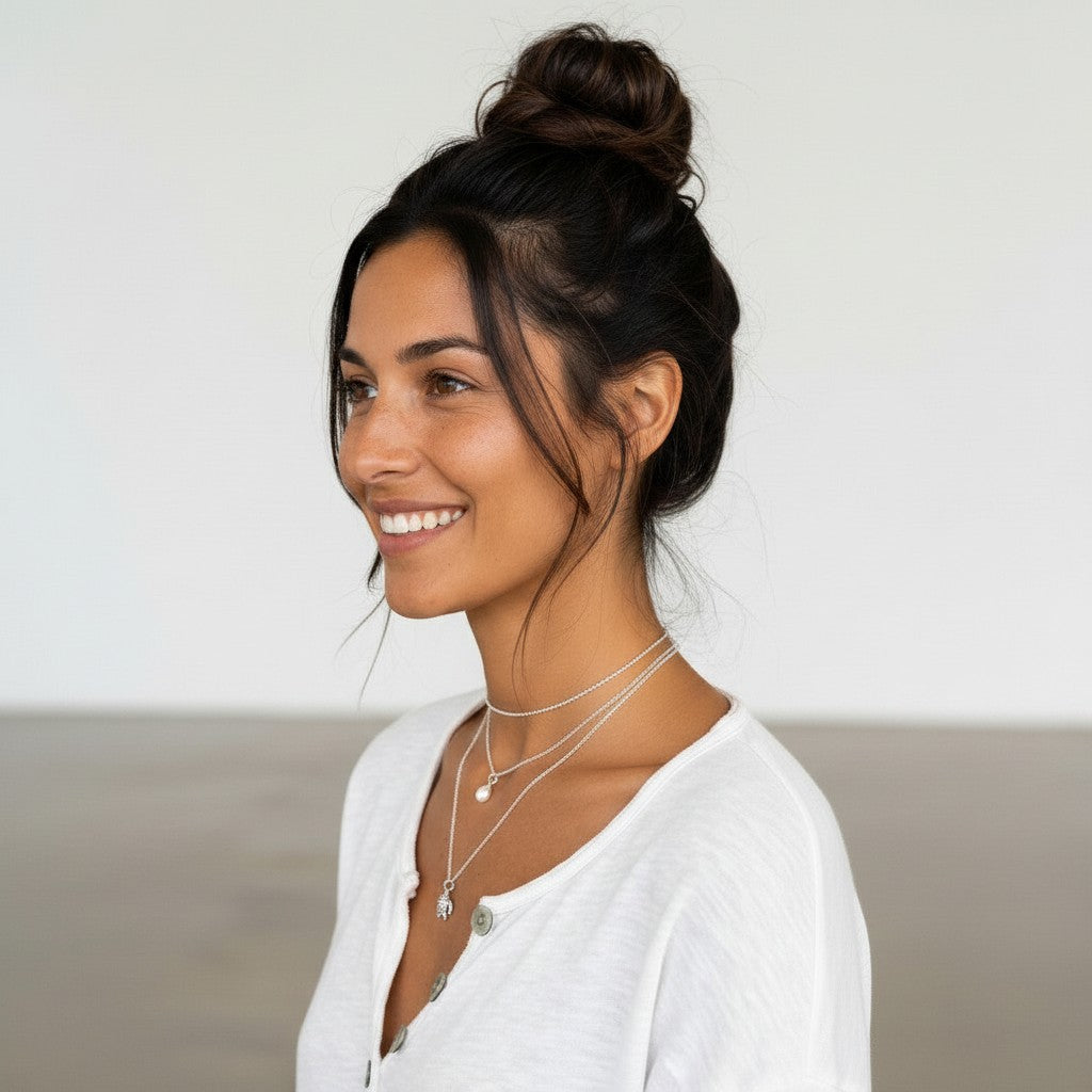 Mujer sonriente con colgante de tortuga de plata de ley de Calendula-shop y cadena fina sobre camiseta blanca
