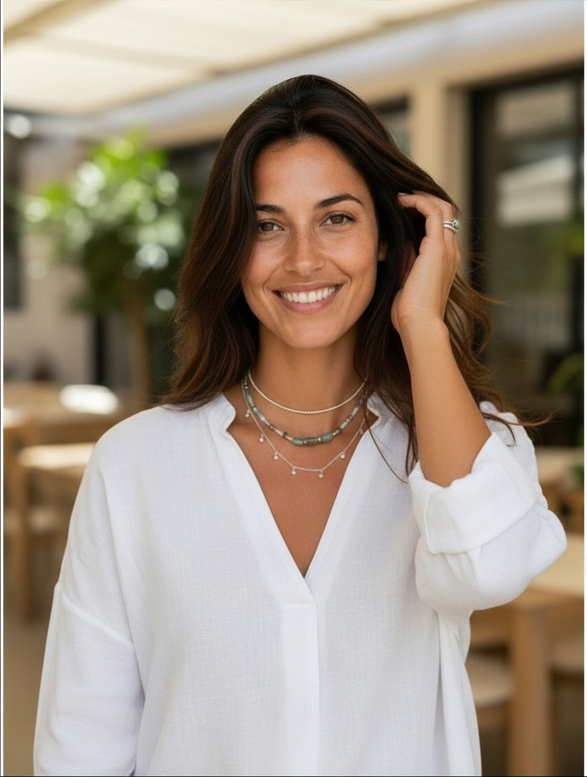 Mujer sonriente luciendo el collar cascada bolitas de plata de ley de Calendula-shop con una blusa blanca