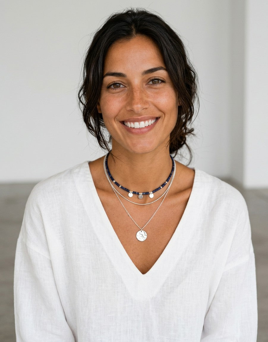 Modelo sonriente luciendo collar de plata de ley con colgante de luna llena de Calendula-shop sobre blusa blanca.