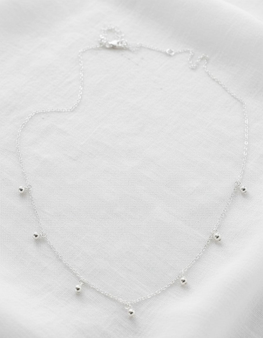 Collar Calendula-shop de plata de ley con cadena fina y siete pequeñas bolitas colgantes sobre fondo blanco