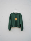 Calendula-shop green cropped sweatshirt with a cute sun illustration on the chest, made of cotton and elastane.
