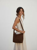 Calendula-shop Niza brown suede shoulder bag worn by a smiling woman in a white linen dress