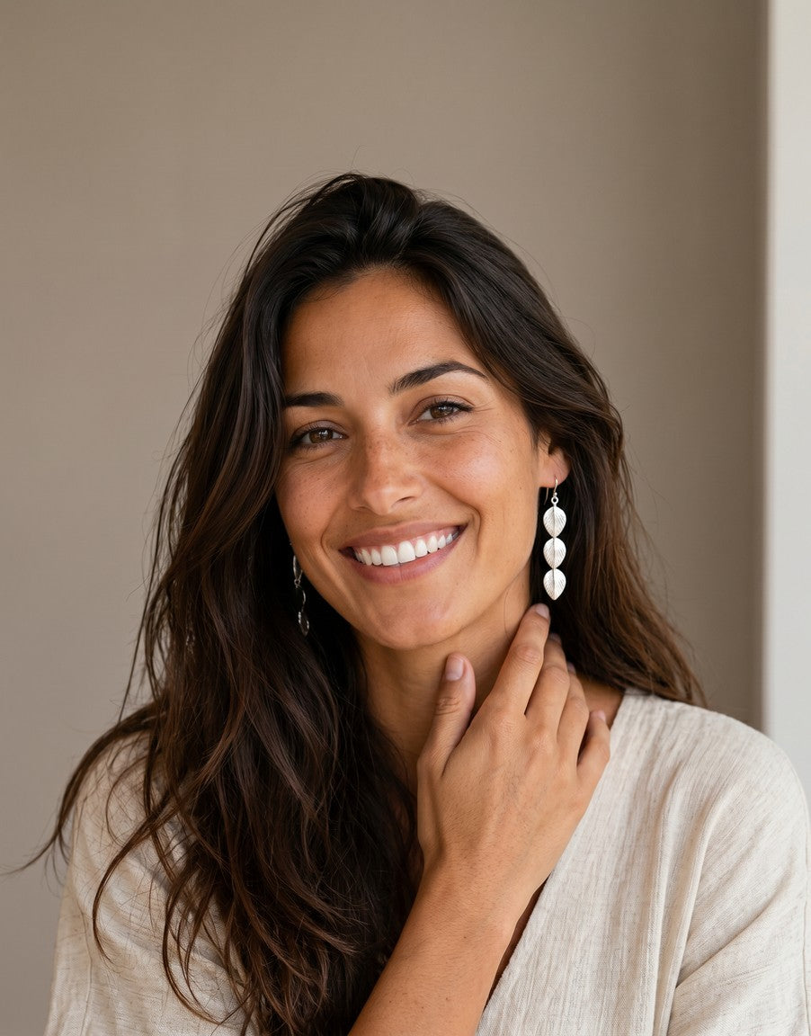 Modelo sonriente luciendo pendientes de plata de ley 925 con diseño de tres hojas de Calendula-shop