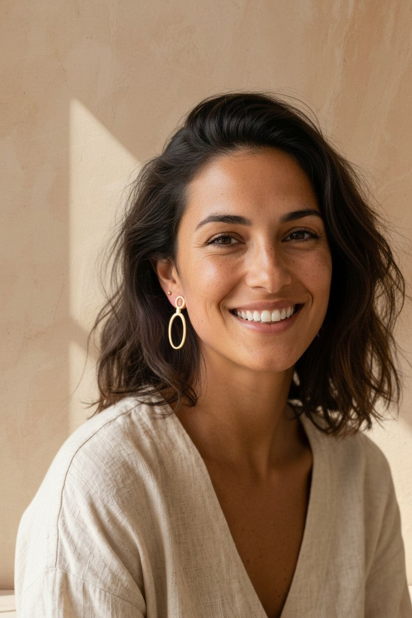 Modelo sonriente luciendo pendientes India de Calendula-shop en plata bañada en oro con diseño de círculo y óvalo.