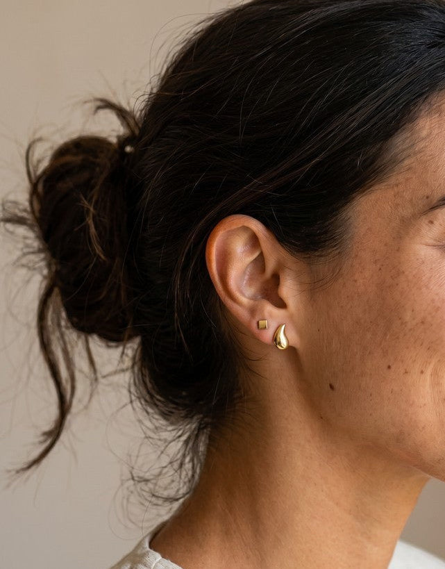 Pendientes mini Calendula-shop de plata bañada en oro con formas geométricas puestos en la oreja de una mujer