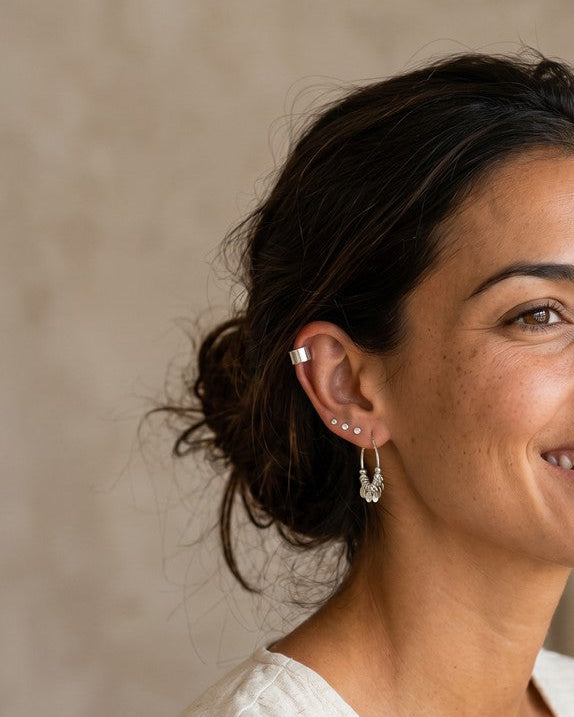 Mujer sonriente luciendo pendientes mini de plata de ley de Calendula-shop en diferentes formas geométricas