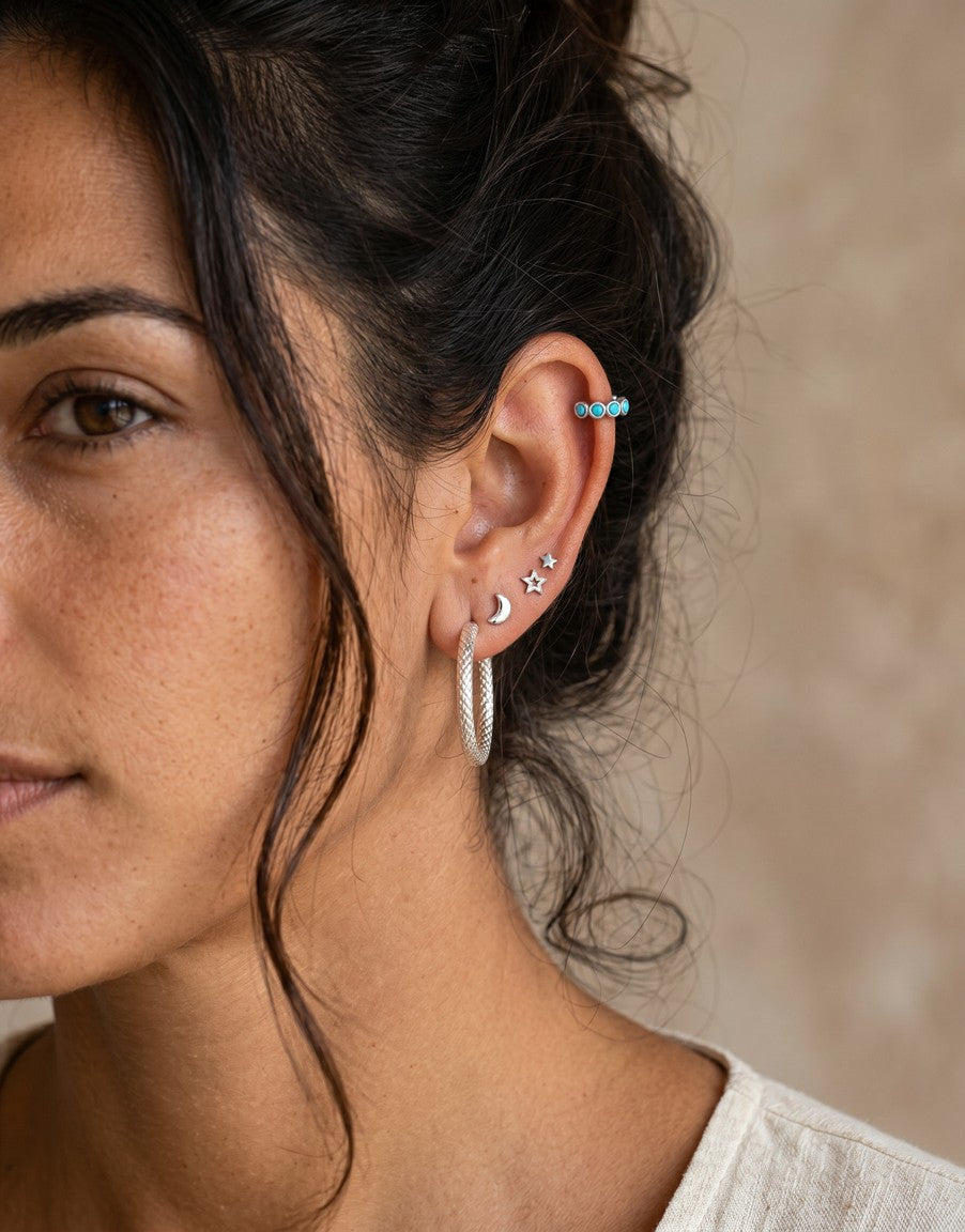 Pendientes mini de Calendula-shop con forma de luna y estrella en plata, lucidos en la oreja de una modelo.