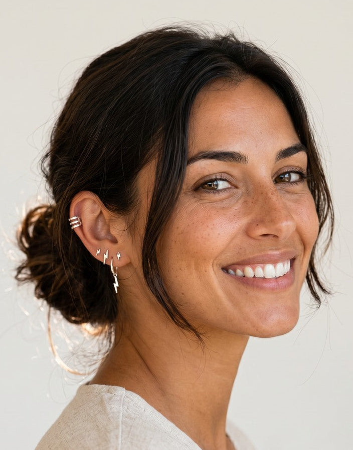 Modelo sonriente luciendo pendientes mini de rayo en plata de ley 925 de Calendula-shop en la oreja
