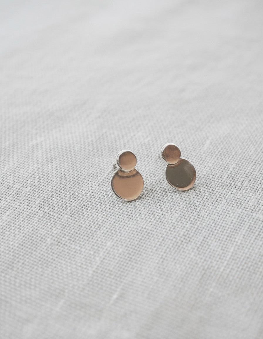 Pendientes Mimosa de Calendula-shop en plata de ley 925 con diseño de dos círculos superpuestos sobre fondo textil