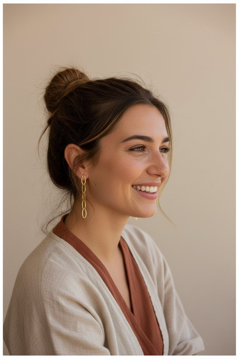 Modelo sonriente luciendo pendientes Vega de Calendula-shop, diseño de cinco eslabones en plata de ley con baño de oro
