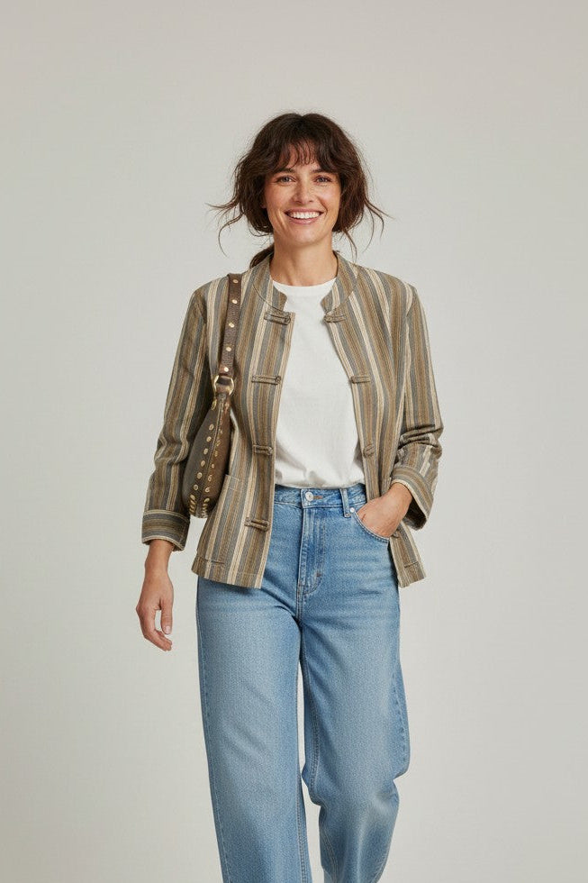 Calendula-shop Petra oval leather crossbody bag with stud details worn by a smiling woman in a striped jacket