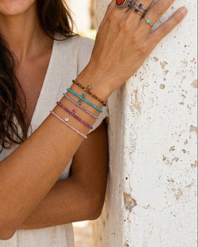 Modelo sonriente luciendo pulseras de bolitas de piedras naturales y plata bañada en oro de Calendula-shop.