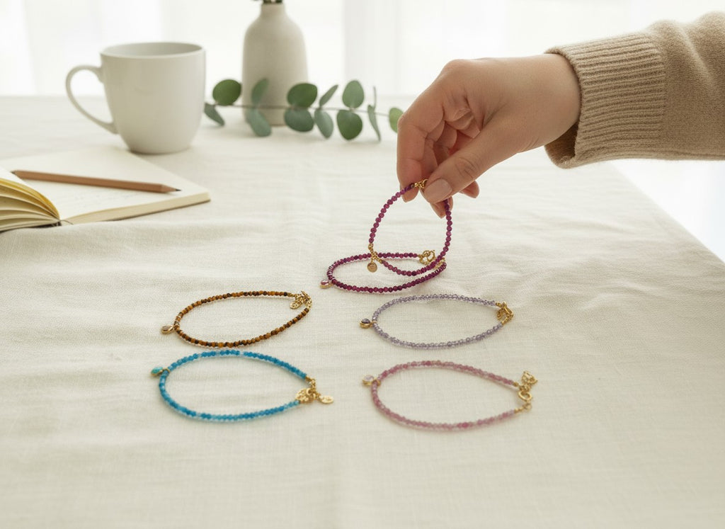 Pulseras Calendula-shop de plata bañada en oro con bolitas de piedras naturales coloridas sobre mesa de estilo nórdico.