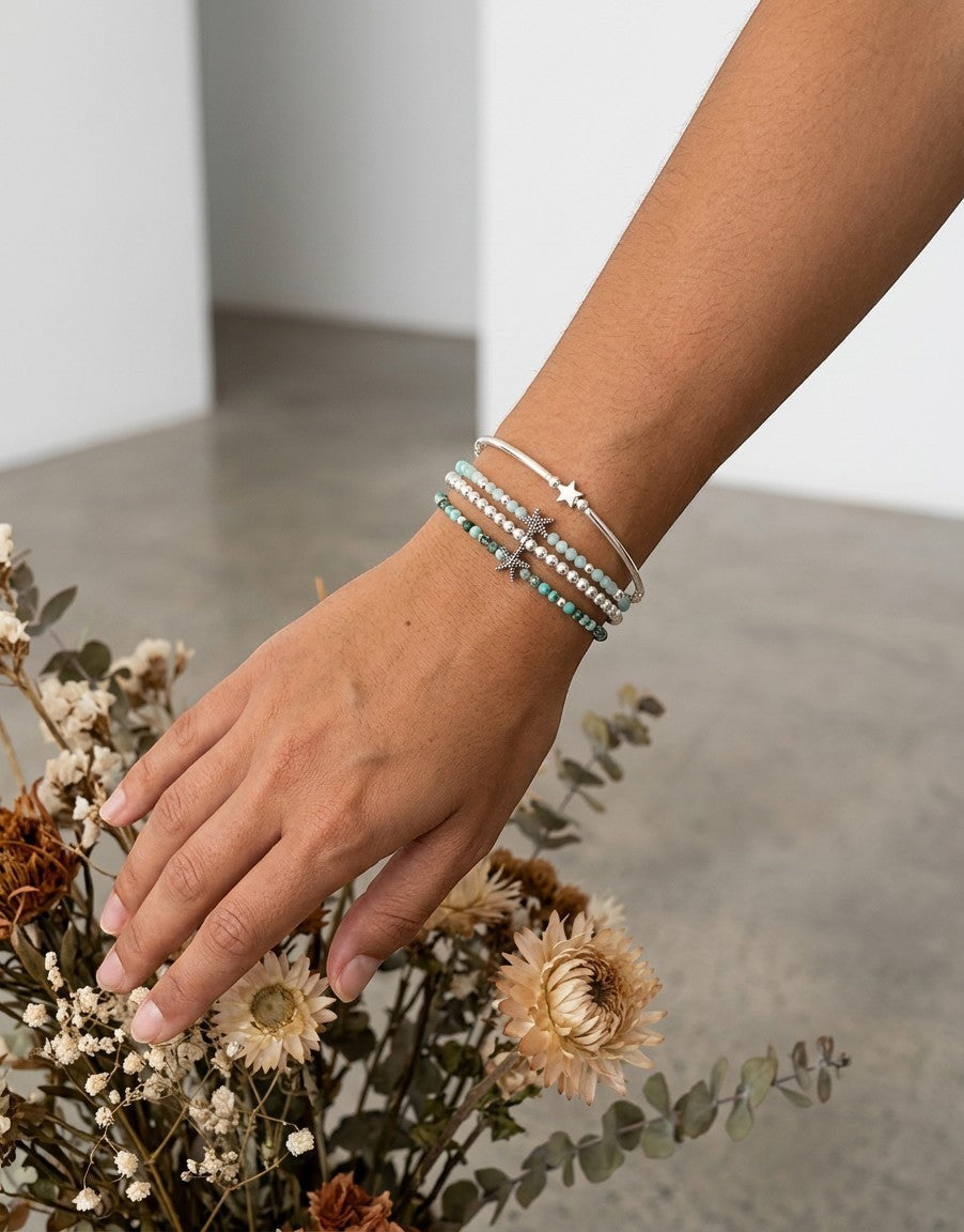 Pulsera Calendula-shop de plata 925 con piedras de aguamarina y detalle de estrella de mar, hecha a mano.