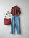 Calendula-shop Sicilia rose canvas tote bag with dual handles, hanging on a white textured wall next to an outfit.