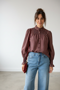 Calendula-shop striped long-sleeve blouse with smocked high neck and cuffs, worn with blue jeans by a woman.