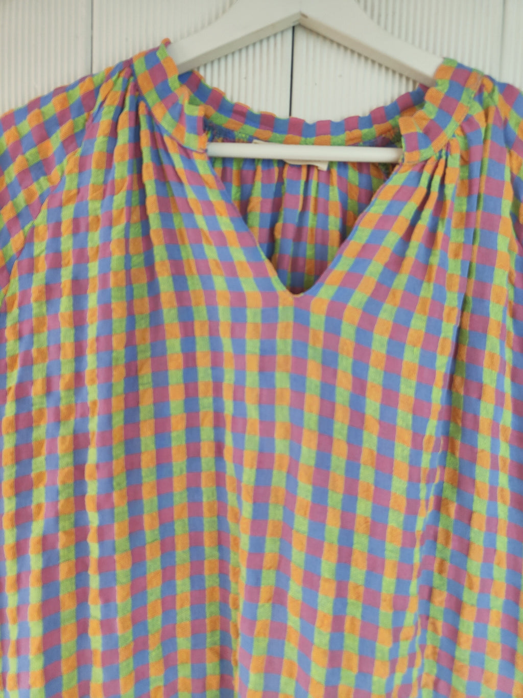Vestido midi oversize de cuadros lilas, azules, naranjas y verdes. Cuello abierto y manga corta. 70% algodón, 30% viscosa.