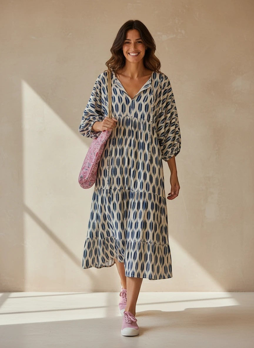 Modelo sonriente con vestido amplio Calendula-shop azul de viscosa, mangas abullonadas y estampado geométrico veraniego